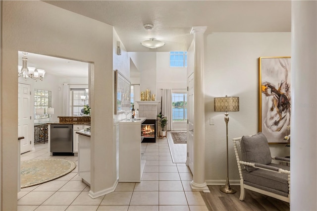 interior space featuring baseboards, a chandelier, light tile patterned floors, and a tile fireplace