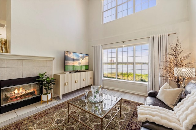 living area featuring a towering ceiling, wood finished floors, and a fireplace