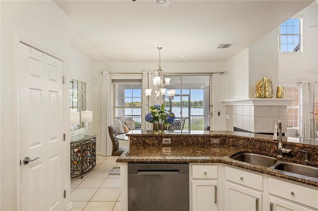 kitchen with a sink, a chandelier, dark stone counters, stainless steel dishwasher, and visible vents