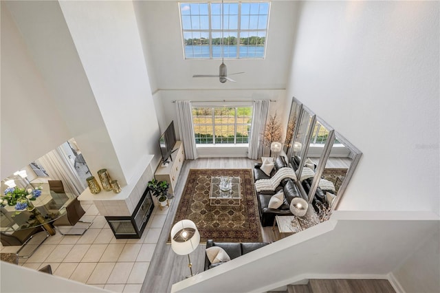 living area featuring ceiling fan, wood finished floors, and a towering ceiling