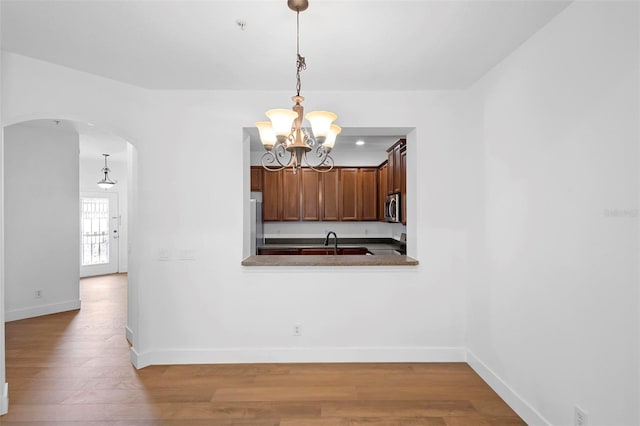 456 Harbor Winds Ct, Winter Springs, FL 32708 - unfurnished dining area with a chandelier, arched walkways, wood finished floors, and baseboards