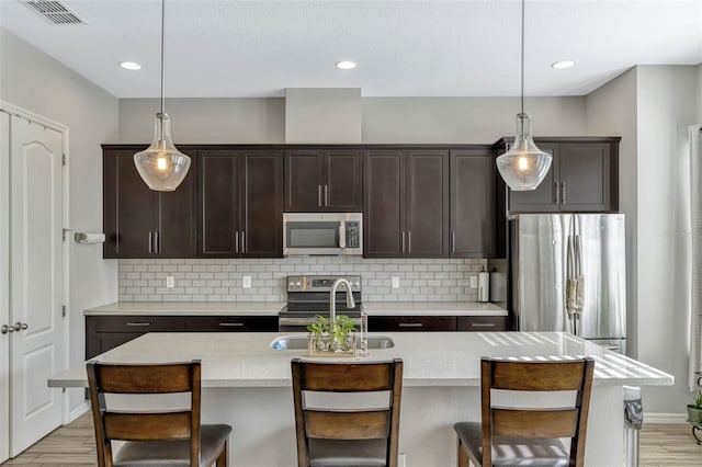861 Taramundi Dr, Oviedo, FL 32765 - kitchen featuring tasteful backsplash, dark brown cabinets, light countertops, appliances with stainless steel finishes, and visible vents