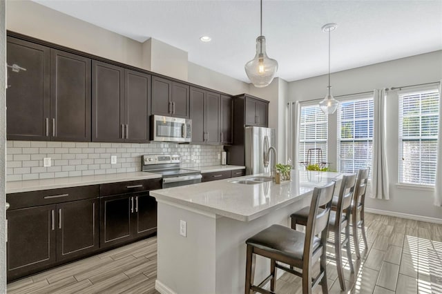 861 Taramundi Dr, Oviedo, FL 32765 - kitchen featuring wood tiled floor, a breakfast bar, a sink, tasteful backsplash, and appliances with stainless steel finishes