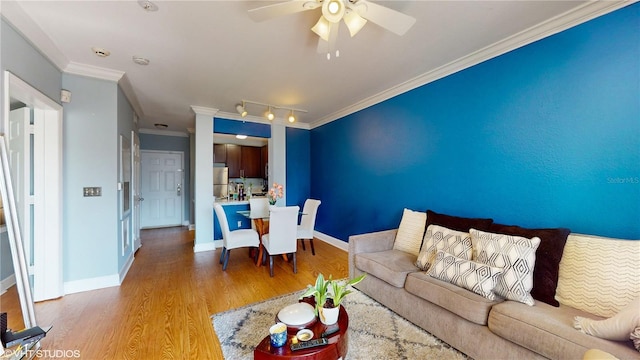 living area featuring crown molding, wood finished floors, baseboards, and a ceiling fan