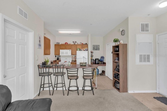 8213 Claire Ann Dr Unit 108, Orlando, FL 32825 - kitchen with white appliances, visible vents, a breakfast bar, and light tile patterned flooring