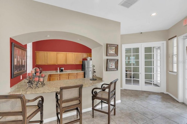 8213 Claire Ann Dr Unit 108, Orlando, FL 32825 - kitchen featuring light brown cabinets, a kitchen breakfast bar, a peninsula, freestanding refrigerator, and visible vents