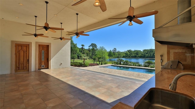 outdoor pool with a ceiling fan, a sink, and a water view