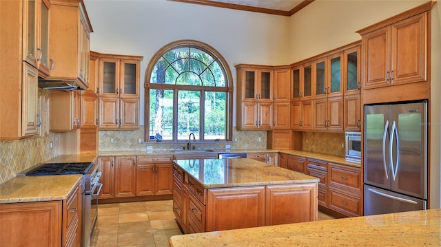 kitchen with light stone countertops, a sink, brown cabinets, and stainless steel appliances