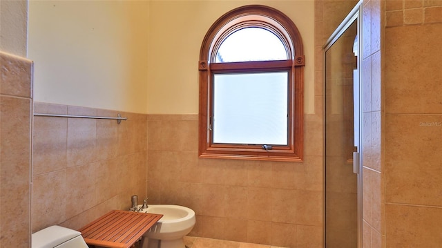 bathroom featuring tile walls, toilet, a bidet, and a tile shower
