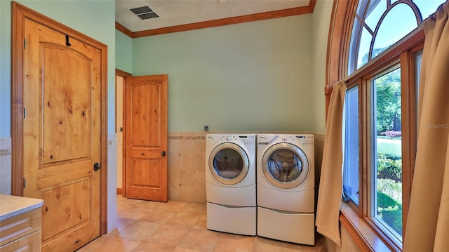 laundry room featuring ornamental molding, separate washer and dryer, cabinet space, and plenty of natural light