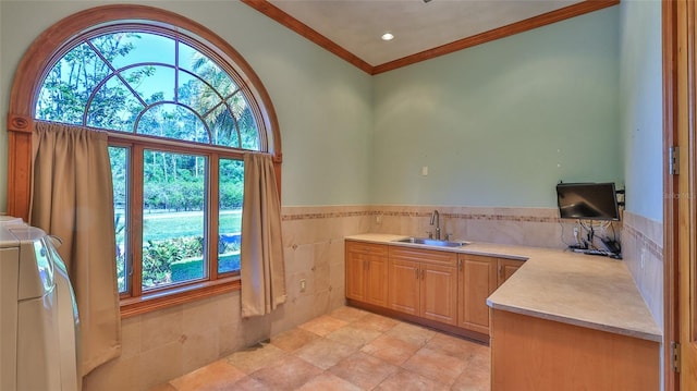 interior space featuring light countertops, a sink, independent washer and dryer, tile walls, and crown molding
