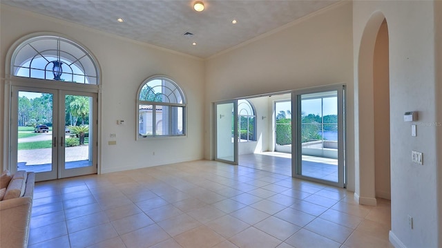 doorway with light tile patterned floors, french doors, crown molding, and baseboards