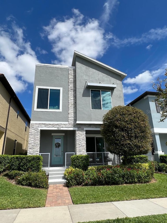 contemporary home featuring stucco siding, stone siding, and covered porch