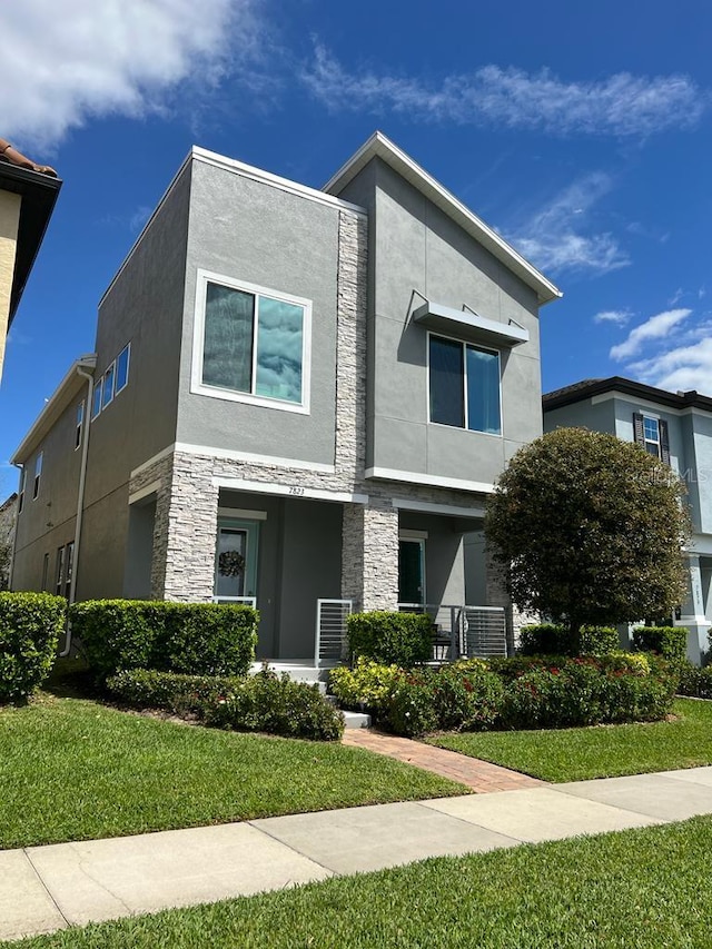 view of front of house featuring a front yard, stone siding, and stucco siding
