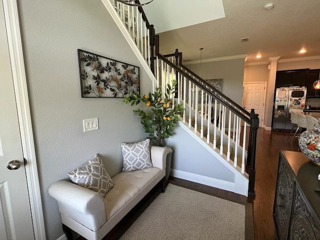 interior space with visible vents, baseboards, a textured ceiling, crown molding, and wood finished floors