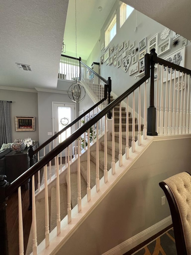 stairway featuring visible vents, baseboards, a wealth of natural light, and a textured ceiling