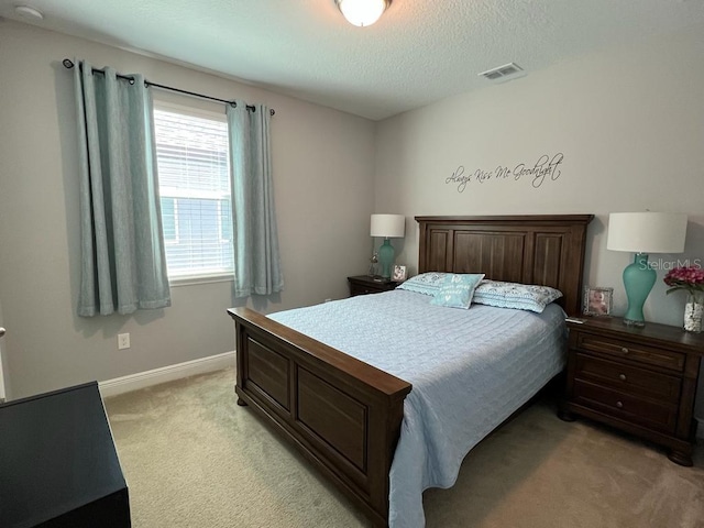 bedroom featuring visible vents, light colored carpet, baseboards, and a textured ceiling