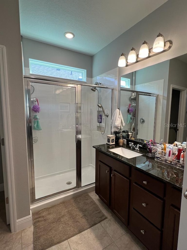full bath with a shower stall, a textured ceiling, vanity, and tile patterned flooring