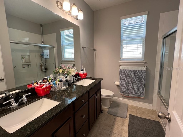 full bath with a sink, toilet, double vanity, and tile patterned flooring