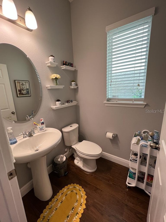 bathroom with toilet, baseboards, and wood finished floors