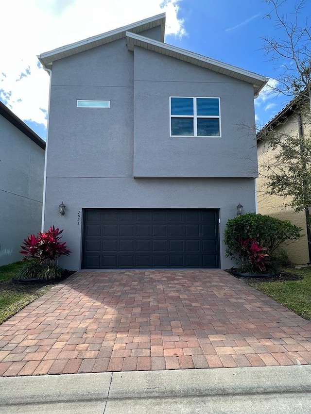 view of front facade with an attached garage, decorative driveway, and stucco siding