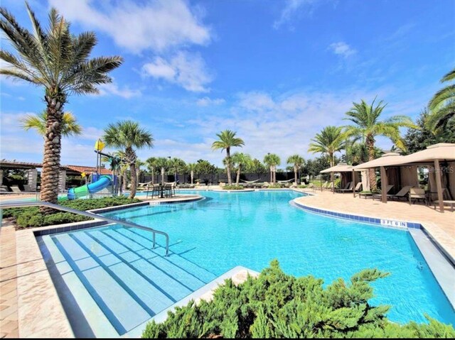 pool featuring a water slide and a patio