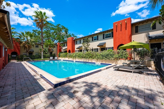 pool with fence, a patio area, and a residential view