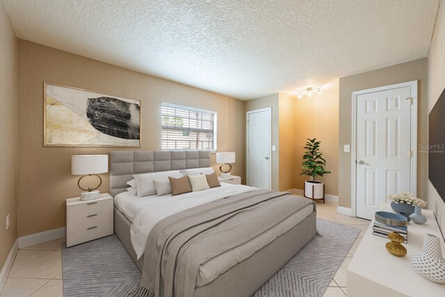 bedroom featuring a textured ceiling, baseboards, and light tile patterned floors