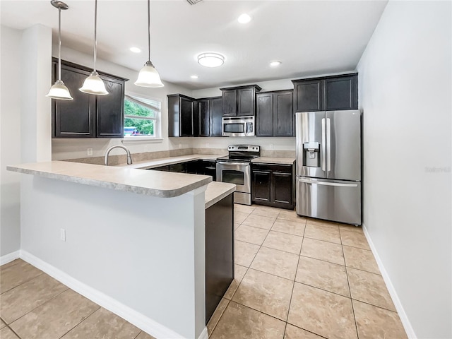 kitchen featuring light tile patterned floors, a peninsula, light countertops, stainless steel appliances, and decorative light fixtures