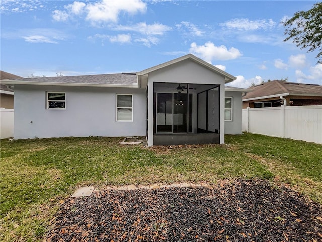 rear view of house with a sunroom, stucco siding, fence, and a lawn