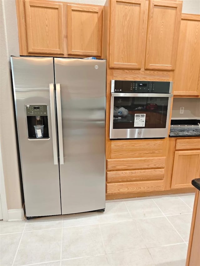 9046 Tuscan Valley Pl, Orlando, FL 32825 - kitchen with stainless steel appliances, light tile patterned floors, light brown cabinetry, and dark countertops