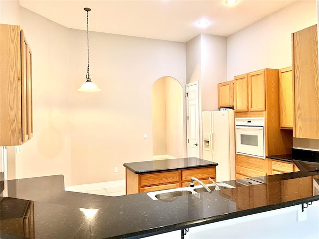 9046 Tuscan Valley Pl, Orlando, FL 32825 - kitchen with dark stone countertops, a center island, a sink, white appliances, and a peninsula