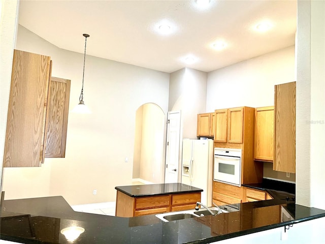 9046 Tuscan Valley Pl, Orlando, FL 32825 - kitchen featuring dark stone countertops, decorative light fixtures, a sink, white appliances, and a peninsula