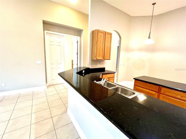 9046 Tuscan Valley Pl, Orlando, FL 32825 - kitchen featuring hanging light fixtures, baseboards, arched walkways, a sink, and light tile patterned flooring