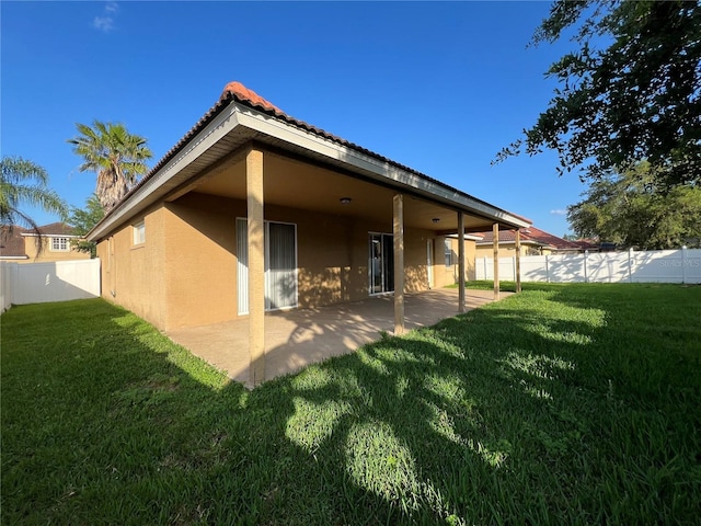 9046 Tuscan Valley Pl, Orlando, FL 32825 - back of house with a fenced backyard, stucco siding, a lawn, a patio area, and a tile roof