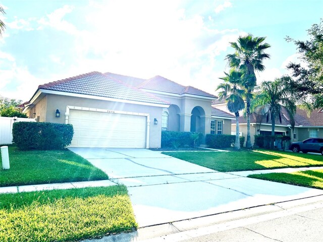 9046 Tuscan Valley Pl, Orlando, FL 32825 - view of front of home with concrete driveway, stucco siding, a front lawn, a garage, and a tiled roof