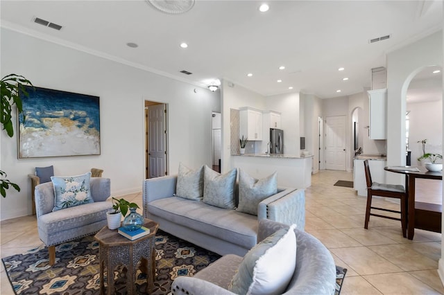 living room with arched walkways, ornamental molding, and recessed lighting