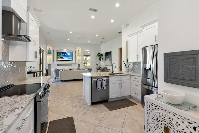kitchen featuring wall chimney exhaust hood, stainless steel appliances, a sink, visible vents, and decorative backsplash