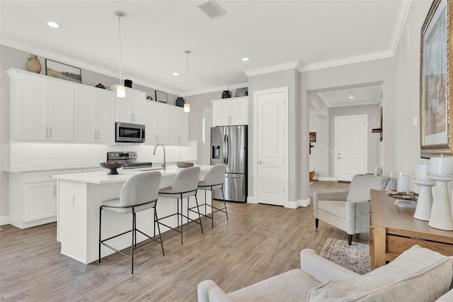 1821 Simonton Ave, Orlando, FL 32806 - kitchen featuring a breakfast bar, an island with sink, visible vents, decorative backsplash, and appliances with stainless steel finishes