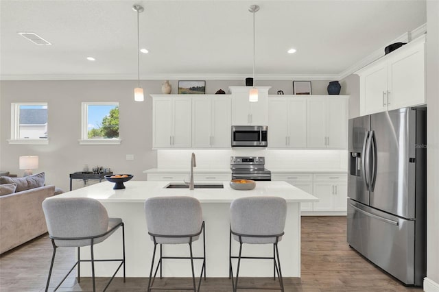 1821 Simonton Ave, Orlando, FL 32806 - kitchen with wood finished floors, ornamental molding, a sink, appliances with stainless steel finishes, and a breakfast bar area