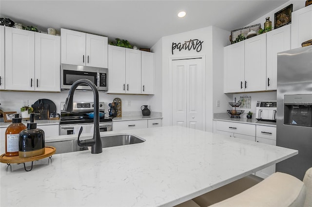 4094 San Clemente Ct, North Fort Myers, FL 33917 - kitchen featuring appliances with stainless steel finishes, light stone counters, white cabinets, and recessed lighting