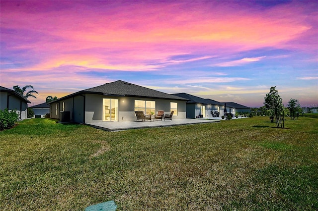 4094 San Clemente Ct, North Fort Myers, FL 33917 - back of property at dusk featuring a patio area, stucco siding, and a lawn