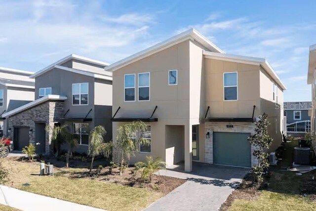 1013 Leader St, Davenport, FL 33896 - view of front of property with an attached garage, stone siding, cooling unit, stucco siding, and driveway