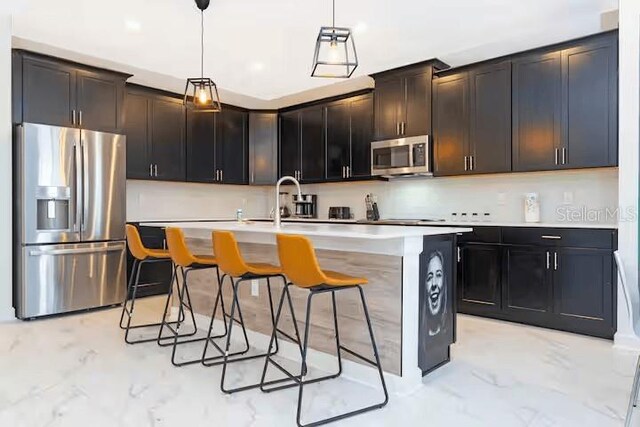 1013 Leader St, Davenport, FL 33896 - kitchen with an island with sink, a kitchen bar, appliances with stainless steel finishes, a sink, and hanging light fixtures