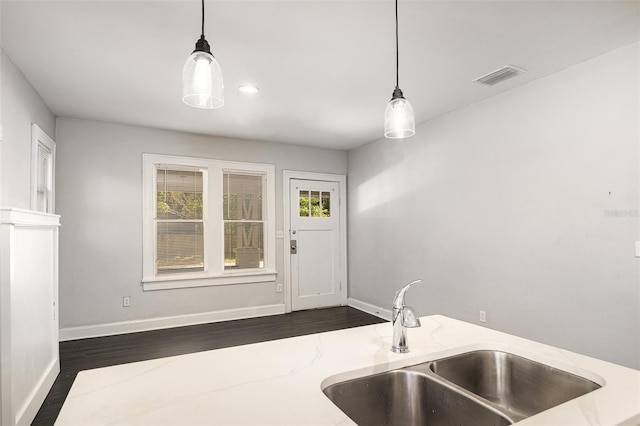 kitchen with hanging light fixtures, a sink, dark wood finished floors, baseboards, and visible vents