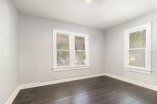 empty room featuring baseboards and dark wood finished floors
