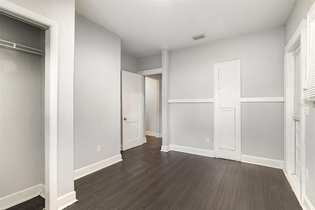unfurnished bedroom with visible vents, baseboards, and dark wood-style floors