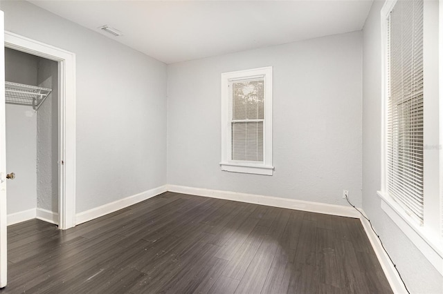 unfurnished bedroom with baseboards, dark wood finished floors, visible vents, and a closet