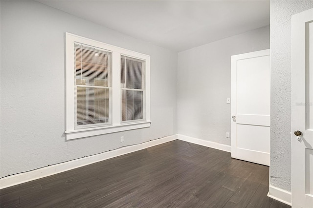 spare room with baseboards and dark wood finished floors