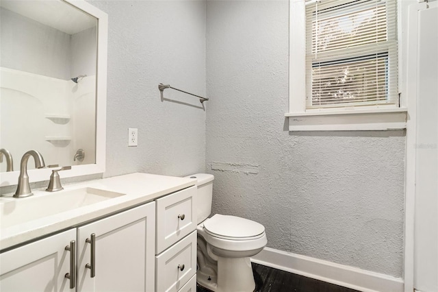 bathroom with vanity, a textured wall, wood finished floors, a shower, and toilet